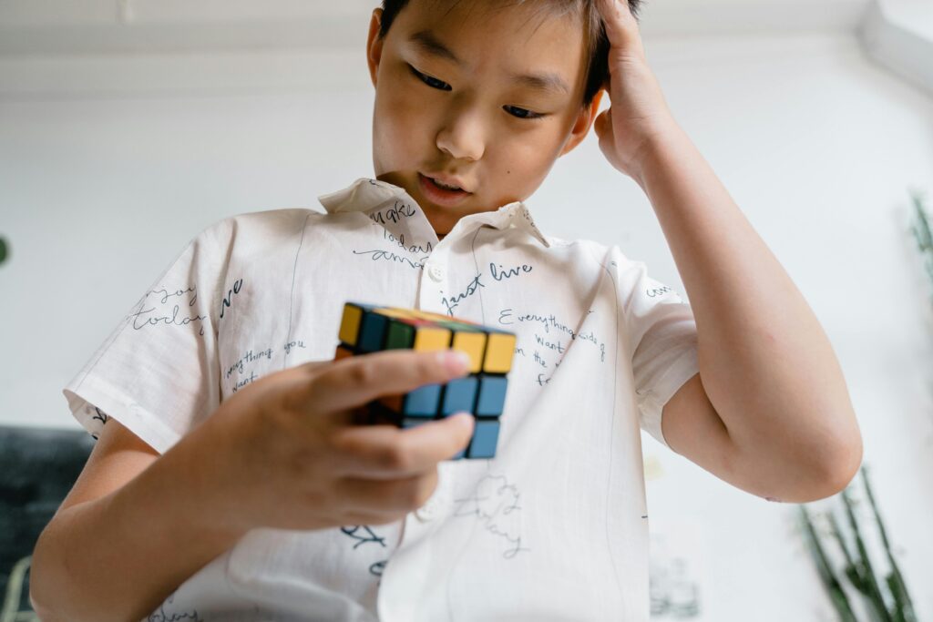 A young boy focused intently on solving a complex puzzle, representing the challenge of overcoming personal development obstacles
